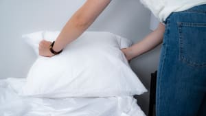 a woman holds the edges of a pillow in a pillow protector