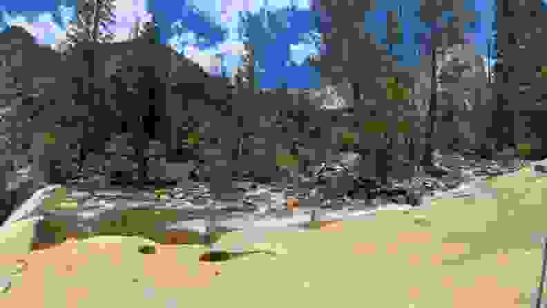 A scenic view of a babbling brook, trees and a mountain on the sunny day.