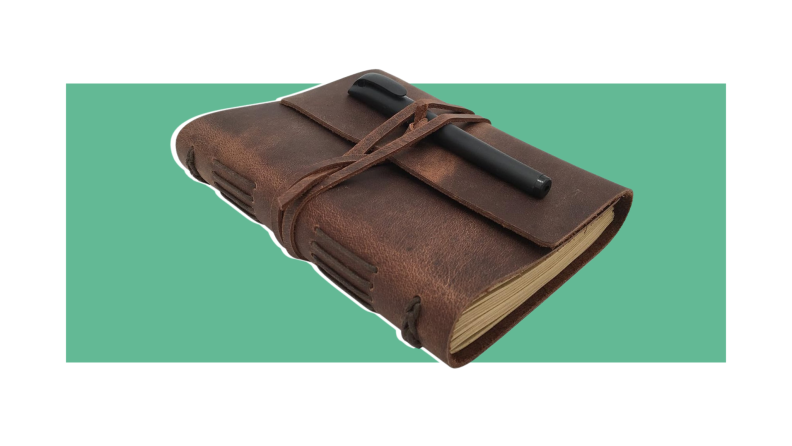 Leather bound journal notebook with pen strapped to front cover by leather string.