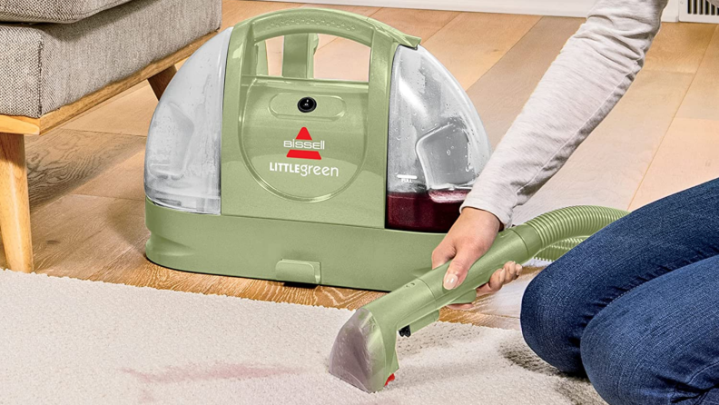 A person cleaning a rug using a Bissell Little Green cleaning machine