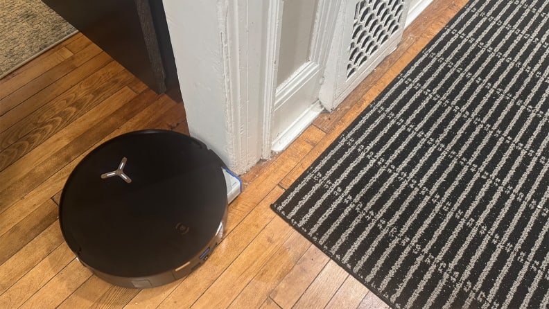 A black robot vacuum in a hallway