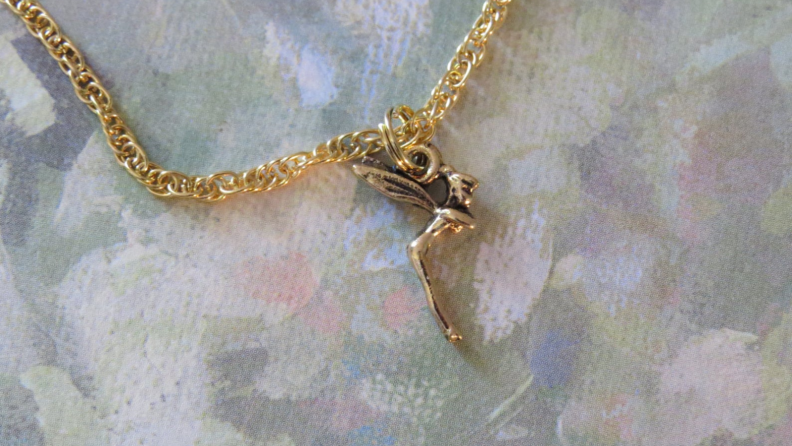 A gold Tinkerbell anklet on a gray background