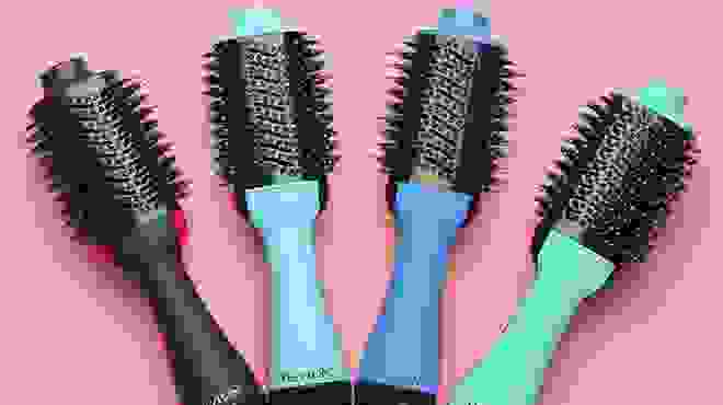 Multiple hair tools in various colors laid out next to each other against a pink background