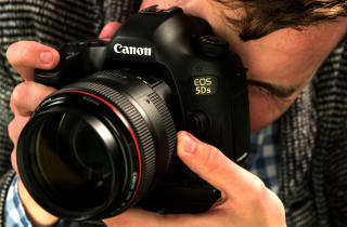 A photographer demonstrates a Canon DSLR camera.