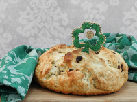 An Irish soda bread is sitting on a cutting board covered with Irish St-Patricks-Day-themed decorations