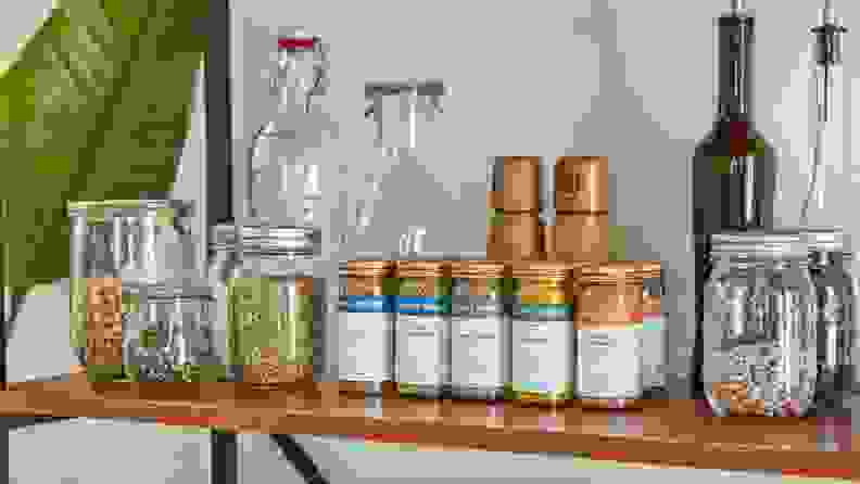 A shelf with glass jars, bottles, and several Spice House jars.