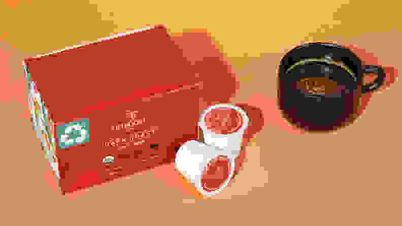 A red box of Lifeboost Coffee's pods and a black cup of coffee next to it, on an orange background.