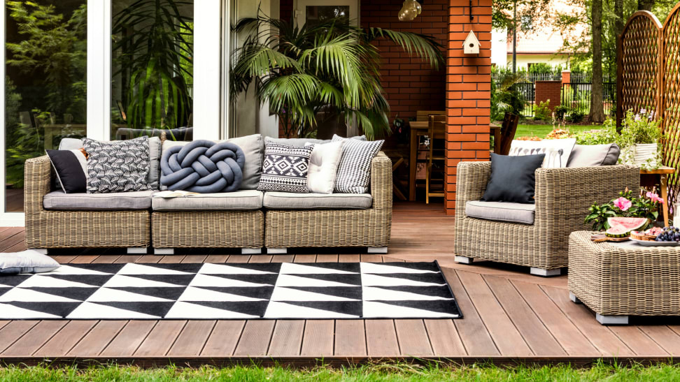 Upscale modern patio furniture with a coffee table, plants, throw pillows.