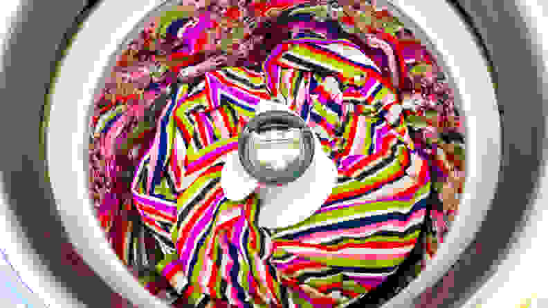 A shot of the interior of the LG WT7305CV Top-loading Washing Machine with Pole Agitator's drum, with a colorful blanket at the bottom for scale.