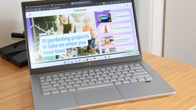 An open and powered-on laptop sitting on top of. light brown wooden surface