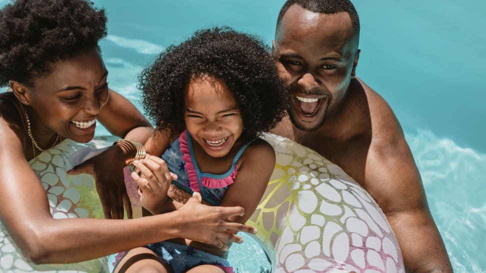 Family of three enjoying fun pool time together with inflatable tube.