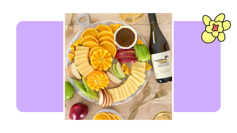 A platter of fruit and cheese, and a bottle of Decoy Chardonnay