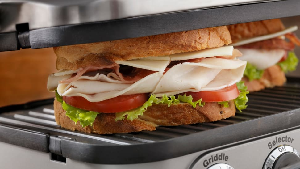 A sandwich  being cooked on an indoor grill.