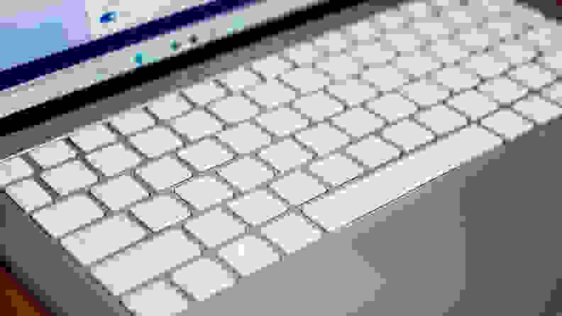 The laptop's keyboard is shown, white keys on a silver chassis.