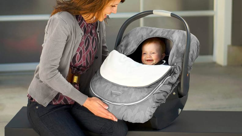 A baby in a car seat that has a cover on it.