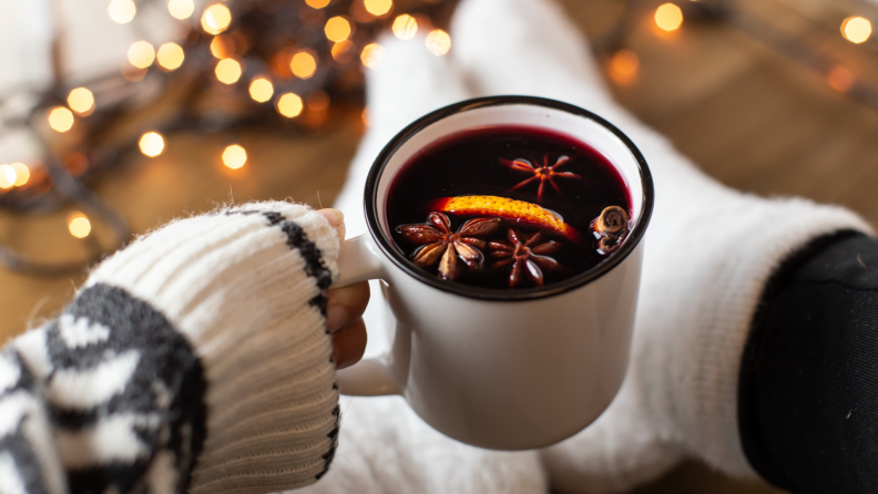 A person clutches a cup of mulled wine.