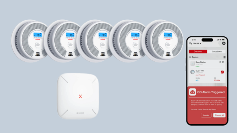 5 smoke detectors, a base, and a phone sit on a gray background