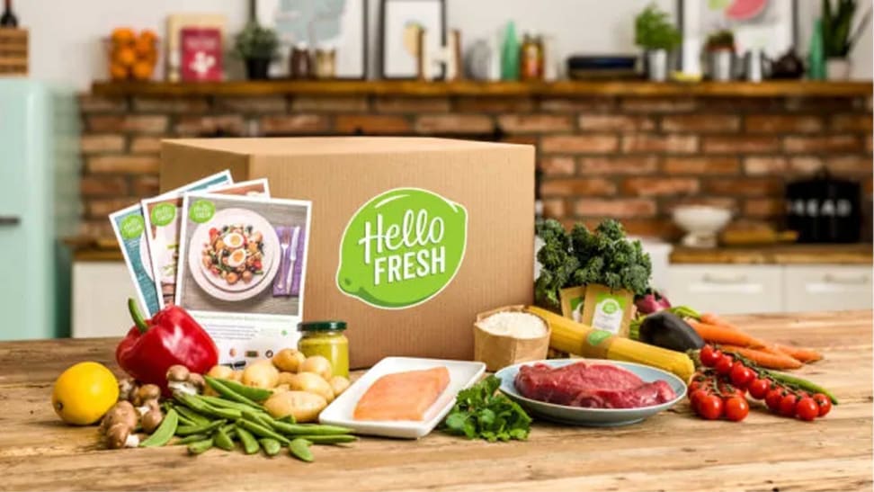 A HelloFresh package surrounded by ingredients in a kitchen setting.