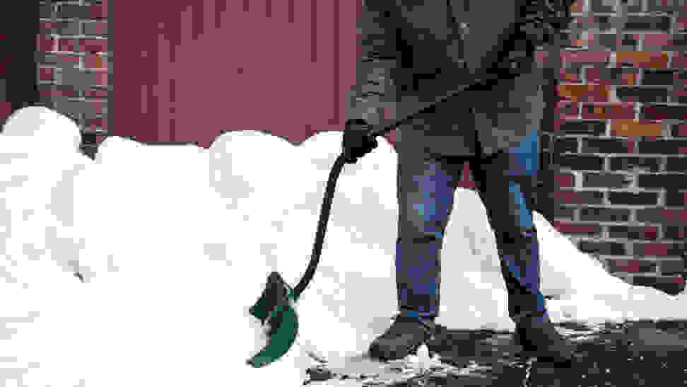 A person shoveling snow with an ergonomic snow shovel.