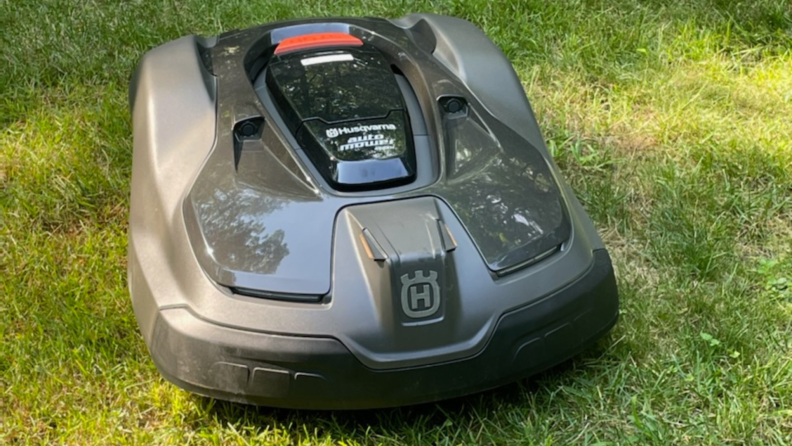 Close-up shot of the gray and black Automower 450XH EPOS robot lawn mower on top of grassy green lawn on sunny day.