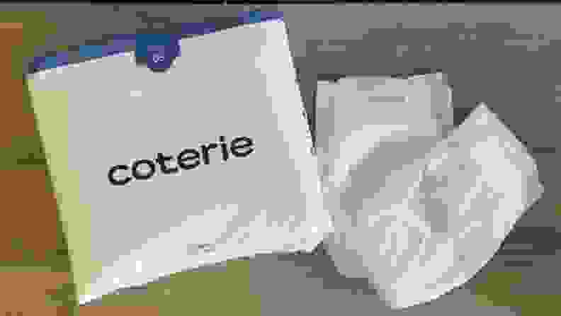 A Coterie package and a several diapers on a table.