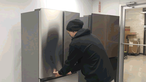 GIF file of a man taking measurements of an empty fridge.