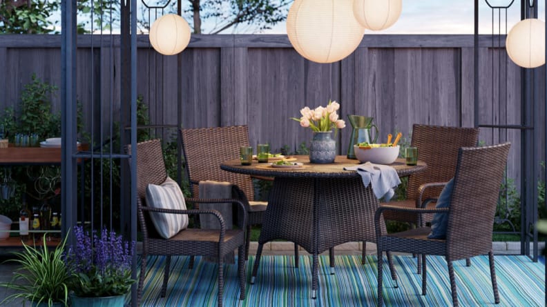 A table with wicker chairs in a backyard setting.