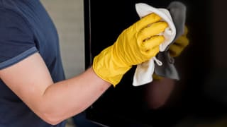 Individual cleaning a flat screen TV