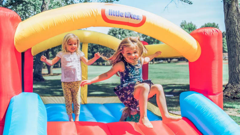 Three children bounce on a Little Tikes inflatable house.