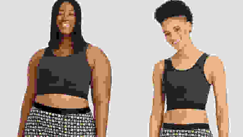 Two people wearing black compression bras smiling on a grey background.
