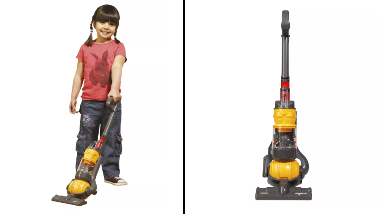 A young child plays with a toy vacuum