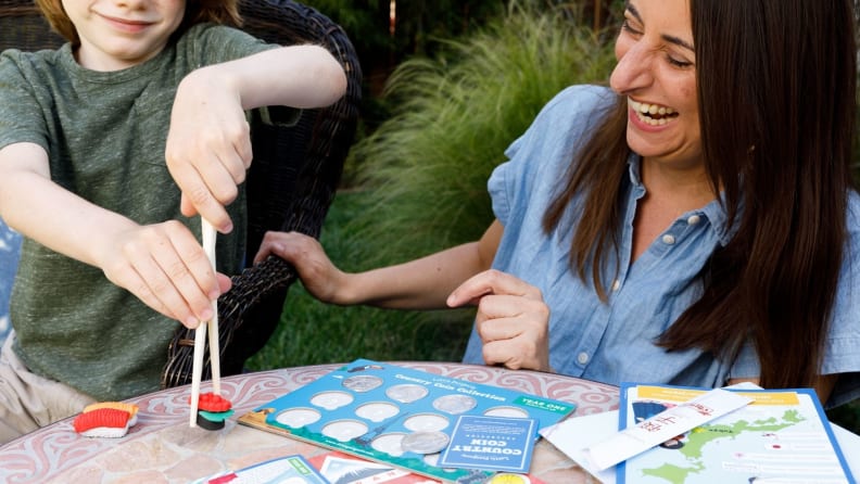 A child picks up toy sushi with chopsticks