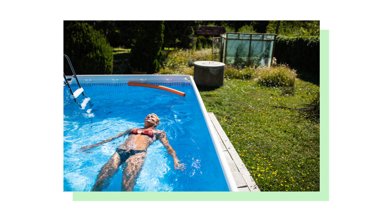 A person floating in an above ground pool in a yard that has grass landscaping.