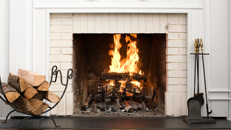 Room with a white brick fireplace with firewood to burn on the side