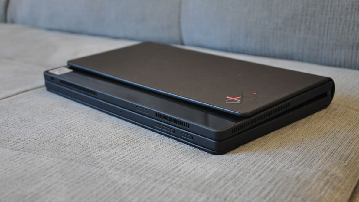 The folded, all-black ThinkPad computer sits on a plush grey cushion like a ledger.