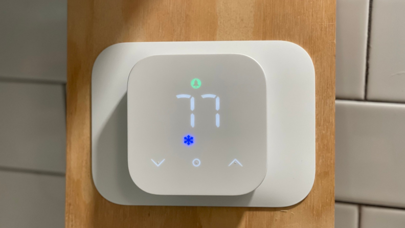 The Amazon Smart Thermostat hanging on a wooden board