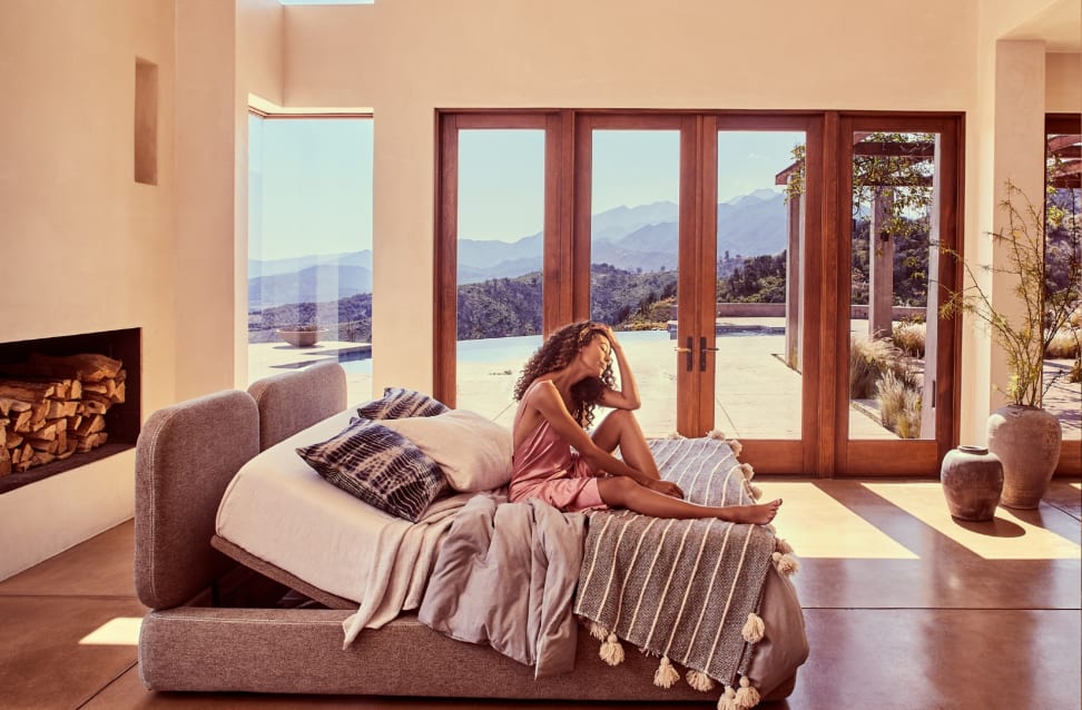 a person sits on an ergomotion bed frame in a sunlit room