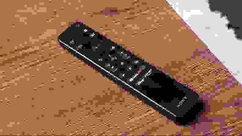 A black Sony television remote sits on a wood table.