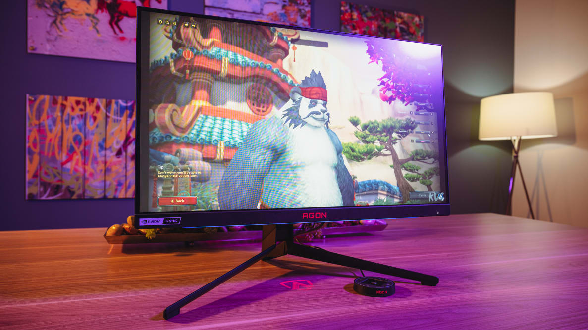 A gaming monitor sitting on top of a wooden desk