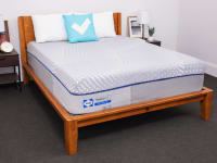The Sealy Posturepedic mattress inside of a wooden frame with two pillows on top indoors.