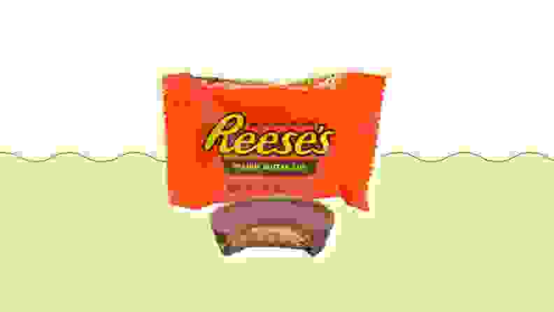 A bitten Reese's cup in front of its accompanying package.
