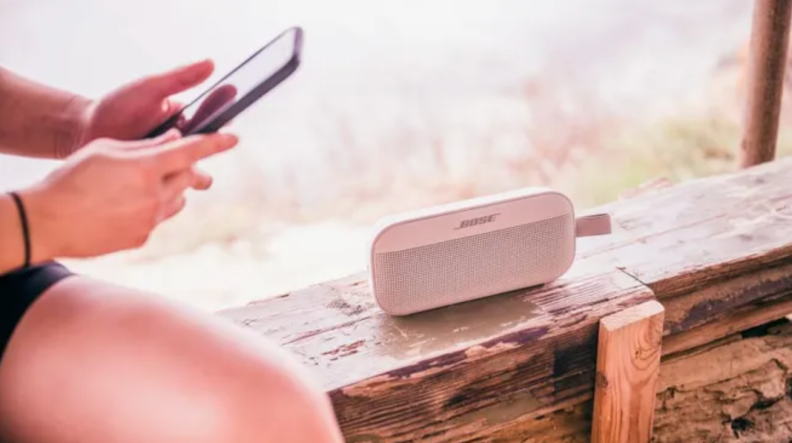 Person using smartphone next to bluetooth speaker.