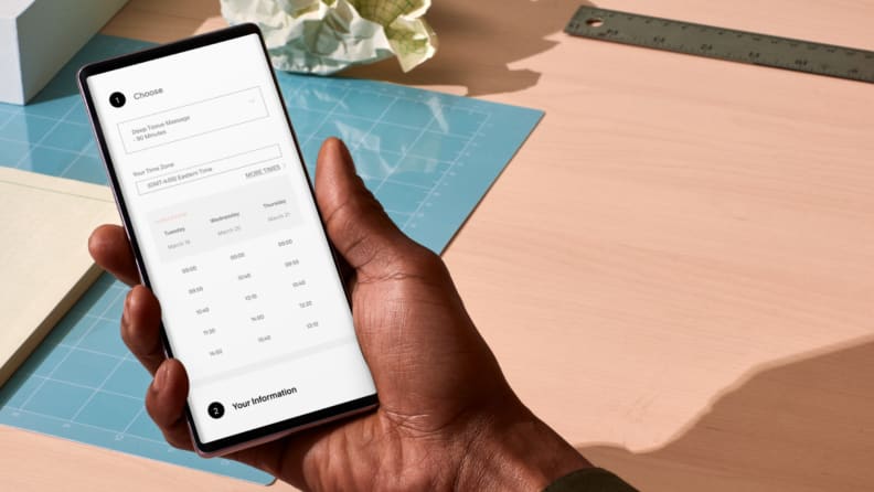 Hand holding a smartphone displaying a mobile appointment booking screen, showing how the best scheduling app for small business enables quick service selection and real-time availability.