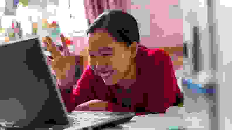 A teenager interacting with a laptop.