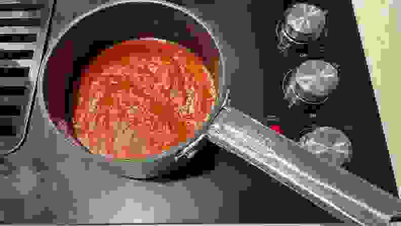 Red sauce cooking inside a pot.