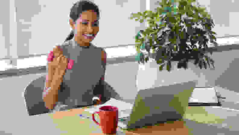 A woman doing a bicep curl at her desk.