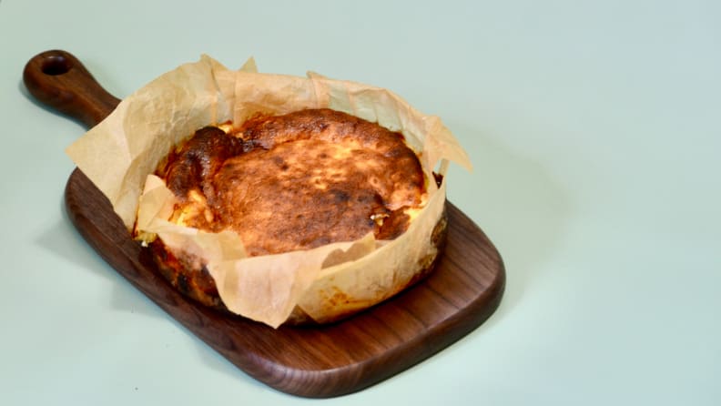 A small homemade Basque cheesecake is served on a wooden cutting board.