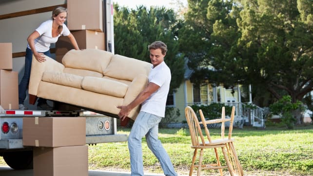 Man and woman loading couch into a truck