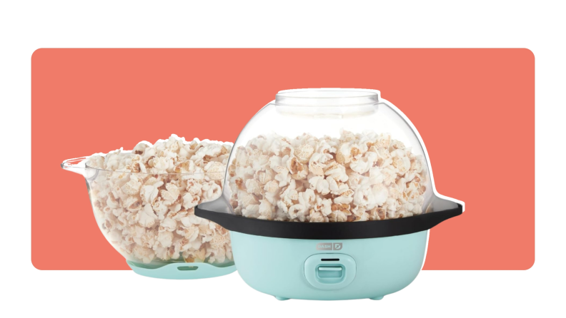A Dash Popcorn Maker filled with popcorn next to a glass bowl of popcorn.