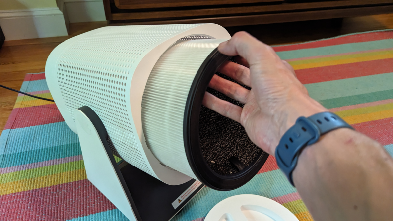 A person holding up the Coway Airmega Aim air purifier.